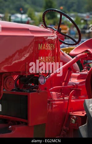 Partial close-up of old, classic, bright red Massey Harris vintage tractor, an exhibit parked at country show - The Great Yorkshire Show, England, UK. Stock Photo