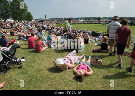 Large crowd of people gathered around main arena, lying or sitting in the sun, watching horse jumping event at The Great Yorkshire Show, England, UK. Stock Photo