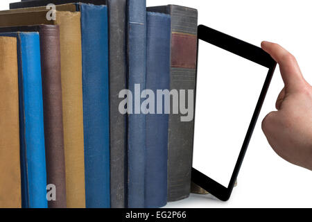 a hand pulling a tablet computer out of a row of books isolated on white background Stock Photo