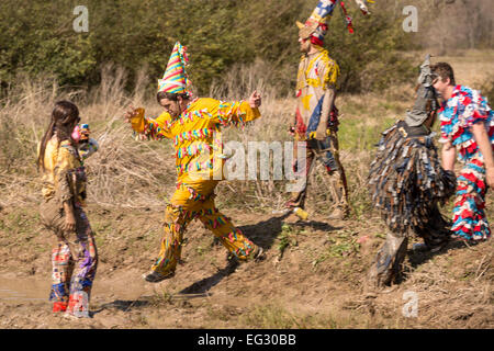 Wearing traditional Cajun Mardi Gras costume and mask runners chase a chicken during the Courir de Mardi Gras February 14, 2015 in Elton, Louisiana. Revelers go from house to house begging to gather food for a communal meal and celebrate by dancing for bystanders when successful. Capitaines riding horseback try to control the good natured revelers as they romp through the countryside causing mischief. Stock Photo