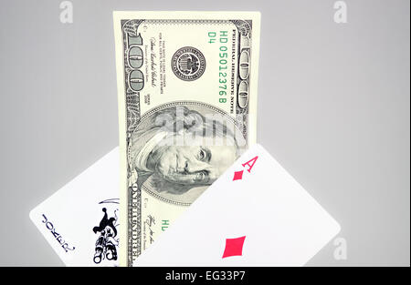 Banknote of one hundred dollars between playing cards on gray background Stock Photo