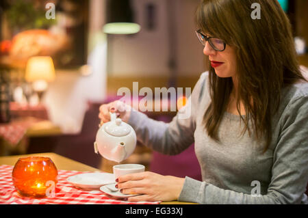 Beautiful young woman enjoying a hot drink with friends in a cosy cafe.