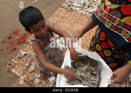 A child working rejects leather pieces on the Hazaribug Embankment in Dhaka. Stock Photo