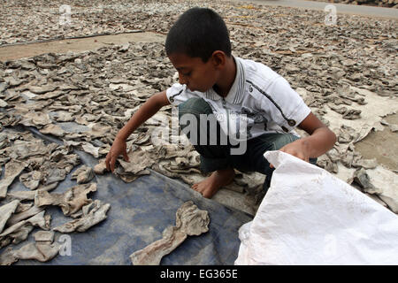 A child working rejects leather pieces on the Hazaribug Embankment in Dhaka. Stock Photo