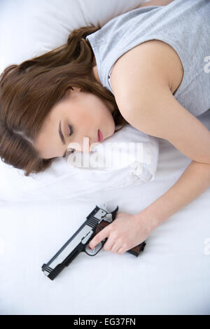 Woman in bed sleeps with hand on gun weapon home security Stock Photo