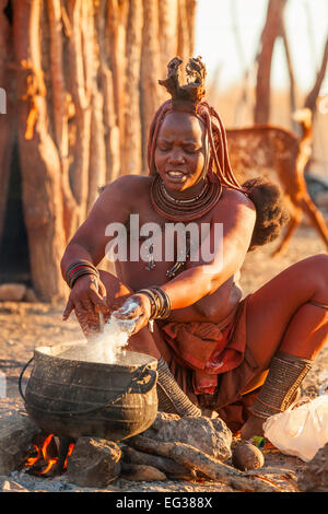 A Himba woman making food. Stock Photo