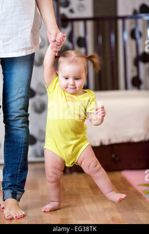 baby taking first steps with mother help Stock Photo