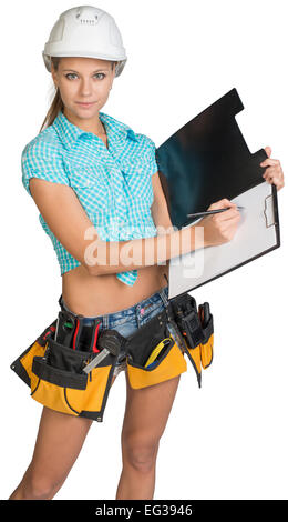 Woman in hard hat and tool belt writing on blank clipboard Stock Photo