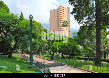 Green lawns and trees of small urban park and modern residential building on background in Monte Carlo, Monaco. Stock Photo