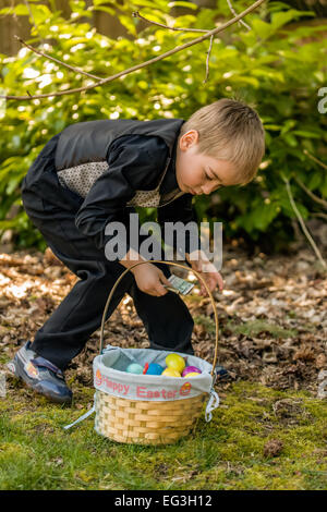 Four year old boy searching for Easter eggs in his backyard, and amazed to find a dollar bill in one of them Stock Photo