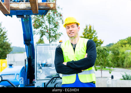 builder or driver driving excavator on construction or building site Stock Photo