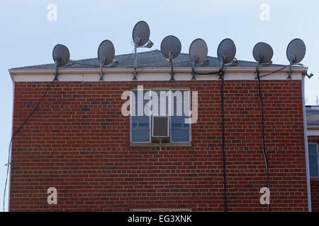 TV satellite dishes mounted on exterior of apartment building - Virginia USA Stock Photo