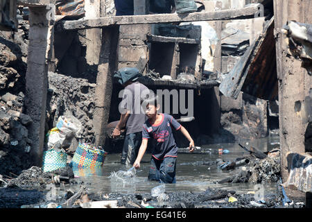 Pasay City, Philippines. 16th Feb, 2015. Residents scavenge for their belongings from a creek after a fire at a slum area in Pasay City, the Philippines, Feb. 16, 2015. At least four people were killed after a fire razed about 300 houses made of light materials, local media reported. Credit:  Rouelle Umali/Xinhua/Alamy Live News Stock Photo