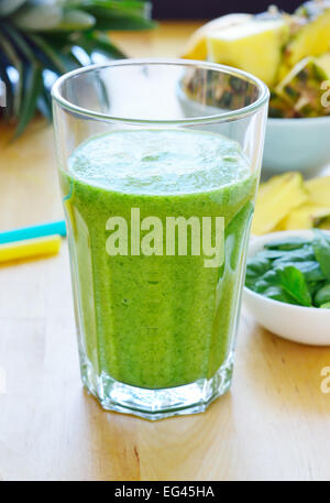 Green spinach and pineapple smoothie on table. Fruit smoothie made with baby spinach leaves, pineapple, banana and pear Stock Photo