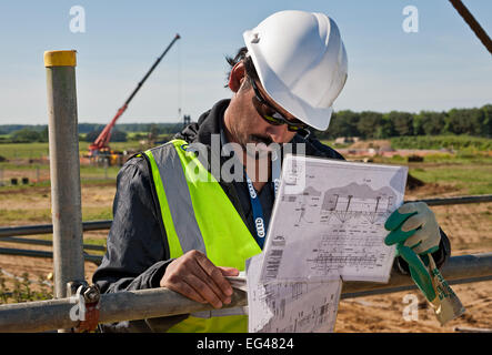 Construction site worker examines building plans on a building site Stock Photo