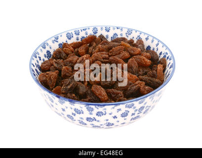 Sultanas in a blue and white porcelain bowl with a floral design, isolated on a white background Stock Photo
