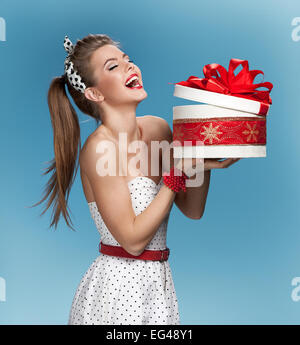 Surprised laughing beautiful young woman holding an open gift box over blue background. Holidays, holiday, celebration, birthday Stock Photo