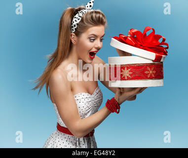 Portrait of happy woman opening gift box against blue background. Holidays, holiday, celebration, birthday and happiness concept Stock Photo