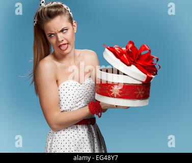 Girl is not satisfied with her gifts against blue background. Holidays, holiday, celebration, birthday concept Stock Photo