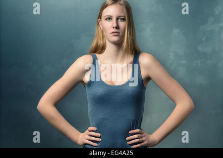 Serious attractive young woman with an attitude standing akimbo with her hands on her hips staring intently at the camera Stock Photo