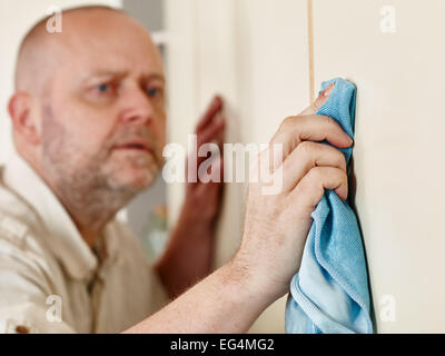 Homeworks, persnickety male cleans the cupboard doors, focus on hand Stock Photo