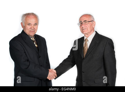 two senior businessmen standing in fron of white background shaking hands Stock Photo