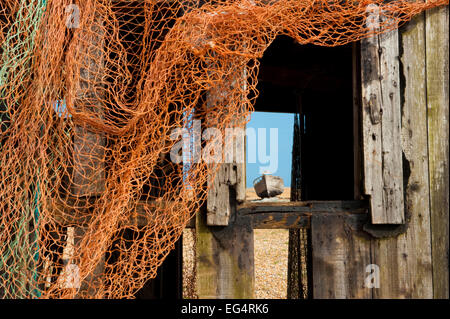 Old wrecked boat on Dungeness beach seen though window of fishermans hut. Stock Photo