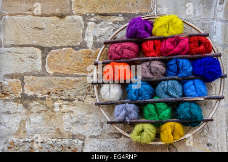 Balls of brightly coloured wool in a circular display on a brick wall Stock Photo