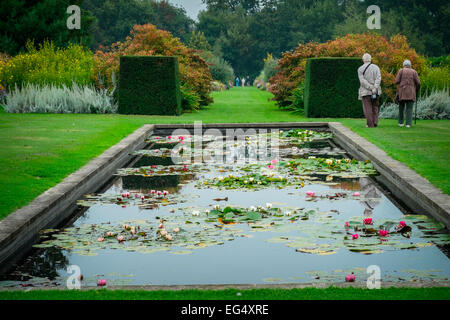 Visitors in formal garden with lily pond. Waterperry Gardens Stock Photo