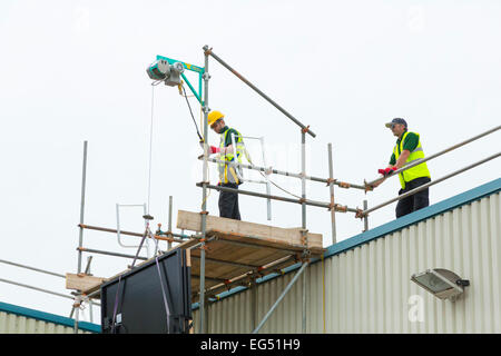 workers using an electric hoist on a construction site Stock Photo