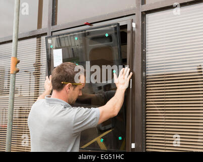 worker installing window frames / replacement glass Stock Photo