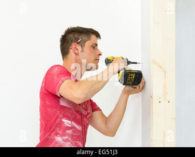 construction worker using a cordless drill to construct a drywall Stock Photo