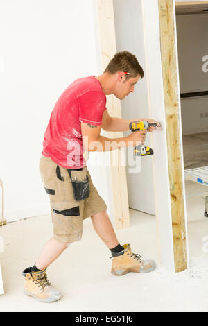construction worker using a cordless drill to construct a drywall Stock Photo