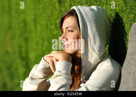Side view portrait of a pensive teenager skater girl thinking with a green blurred background Stock Photo
