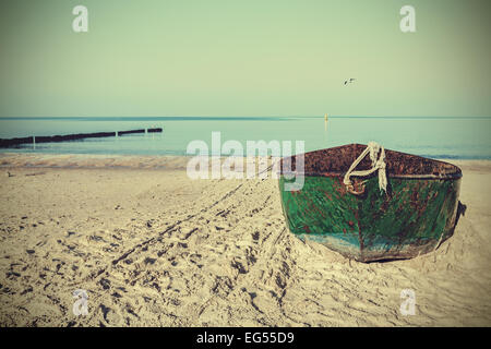 Retro filtered picture of an old rusty steel boat on the beach. Stock Photo
