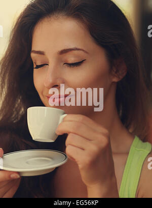 Beautiful happy woman drinking coffee with closed eye. Closeup vintage portrait Stock Photo