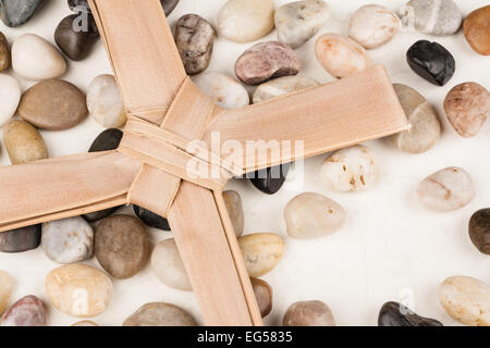 Palm Cross set on multi colored stones. Background for Easter, Good Friday or Palm Sunday. Stock Photo