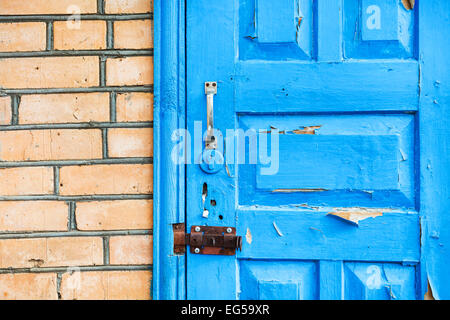 details of closed shabby blue wooden door in brick wall Stock Photo