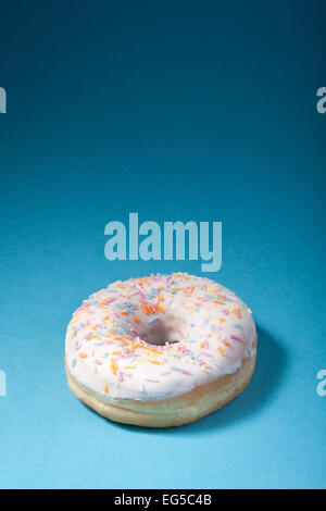 donut with white icing isolated on blue background with copyspace Stock Photo