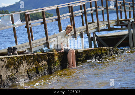 Cooling tired feet while waiting for the ferry at Rowardennan, Loch Lomond, Scotland. Stock Photo