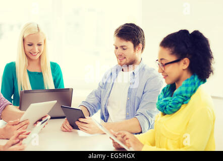 smiling team with table pc and laptop in office Stock Photo