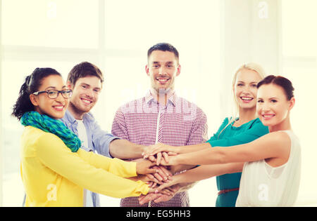 team with hands on top of each other in office Stock Photo