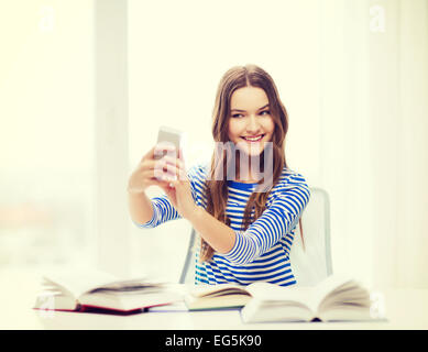 smiling student girl with smartphone and books Stock Photo