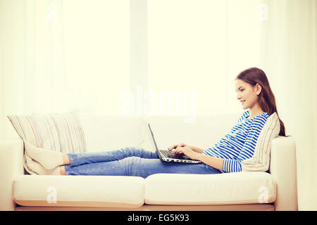 smiling teenage girl with laptop computer at home Stock Photo