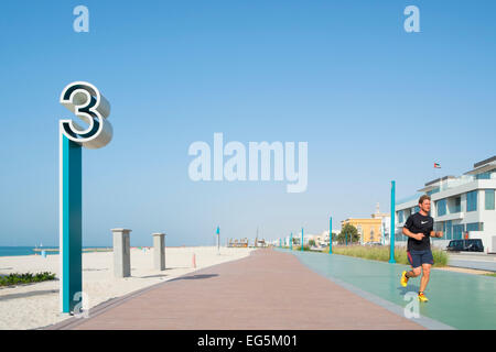 Man jogging along new redeveloped jogging and walking track along beach at Umm Suqueim  in Dubai United Arab Emirates Stock Photo