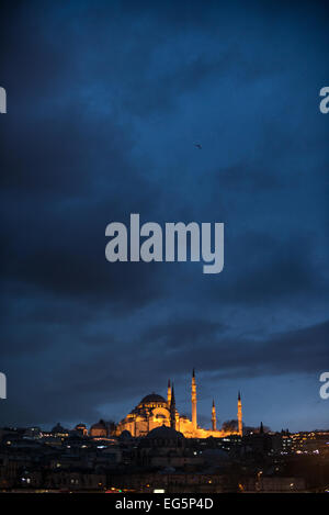 Suleymaniye Mosque At Night Istanbul Turkey / ISTANBUL, Turkey — The Süleymaniye Mosque glows against the night sky on Istanbul's Third Hill, its illuminated dome and four minarets reflected in the waters of the Golden Horn below. Built by Mimar Sinan for Sultan Süleyman I — the longest-reigning Ottoman sultan, who ruled from 1520 to 1566 — the mosque opened for worship on 15 October 1557 and remains in continuous active use today. The four minarets carry a total of ten balconies: three each on the two taller shafts flanking the mosque wall, two each on the shorter pair at the courtyard corner Stock Photo
