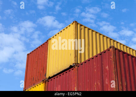 Colorful metal Industrial cargo containers are stacked under blue cloudy sky Stock Photo