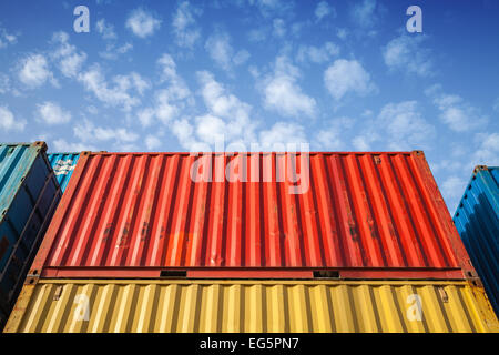 Colorful metal Industrial cargo containers are stacked in the storage area under blue cloudy sky Stock Photo