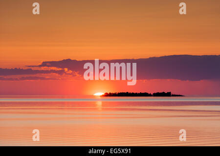 Sunset with sun setting behind silhouetted island in Lake Vänern, largest lake in Sweden at Värmland, Scandinavia Stock Photo