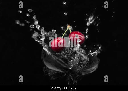 Cherry falling into the water on a black background Stock Photo